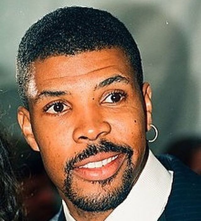 Eriq La Salle smiling in a white shirt and a ring in his left ear.